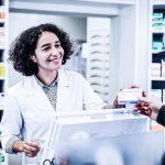 Como aumentar as vendas na farmácia? Na imagem, uma farmacêutica entrega um medicamento a um senhor.